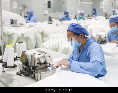 Chongqing, China. Januar 2021. Arbeiter stellen in einer Werkstatt im Landkreis Fengdu in Chongqing, Südwestchina, Schutzanzüge an, 25. Januar 2021. Die Fabrik produziert rund um die Uhr Schutzanzüge, um die Binnennachfrage zu befriedigen, während das Land gegen den jüngsten Ausbruch der COVID-19-Fälle kämpft. Quelle: Liu Chan/Xinhua/Alamy Live News Stockfoto