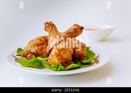 Gekochte Hähnchenschenkel mit Spinat auf weißem Teller. Ausgewogene Mahlzeit. Stockfoto