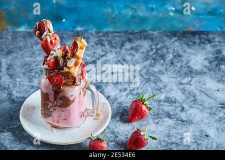 Erdbeer-Smoothie mit Waffeln und Schokolade auf dem weißen Teller Im Marmorhintergrund Stockfoto