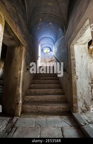 Symmetrische Weitwinkelansicht einer Treppe mit einem blauen Kreuzgewölbe in einem alten und verlassenen Kloster im Zentrum Italien Stockfoto