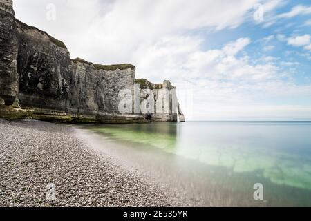 Der weiße felsige Strand von Etretat an einem hellen Sommertag, unter einem blauen Himmel mit Wolken Stockfoto