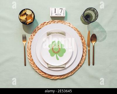 Schöne festliche Tischkulisse für St. Patrick's Day mit Besteck und Glückssymbolen. Draufsicht auf St. Patrick's Tagesferientisch mit grüner Leinentischdecke. Flach liegend. Stockfoto