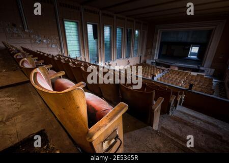 Weitwinkelaufnahme des Innenraums eines alten und verlassenen Kinos, mit den hinteren Reihen im Vordergrund und der Leinwand im Hintergrund Stockfoto