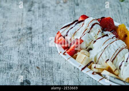 Eis mit Banane, Erdbeere, Orange, Schokolade auf dem weißen Teller Stockfoto