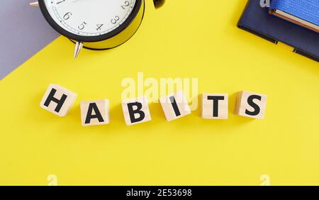 Wort schreiben Text Gewohnheiten auf hölzernen Blöcken.Business-Konzept für regelmäßige Tendenz oder Praxis Routine üblichen Manners Verhalten, gelber Hintergrund. Stockfoto