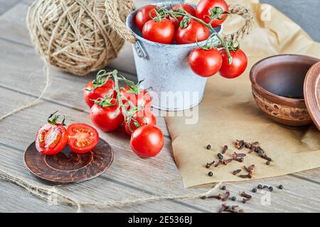 Eimer mit Tomaten und halbgeschnittenen Tomaten auf Holztisch Stockfoto