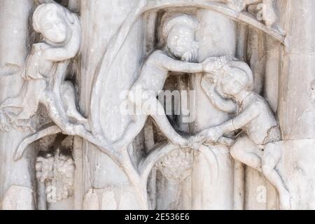 Nahaufnahme eines Flachreliefs aus weißem Marmor an der Fassade Der Kirche porträtiert drei Männer tragen einen Heiligenschein Stockfoto