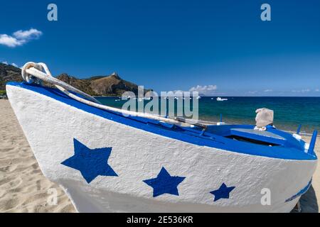 Nahaufnahme eines weißen und blauen Fischerbootes, das an einem sonnigen Sommertag an einem Sandstrand liegt und mit Sternen geschmückt ist Stockfoto