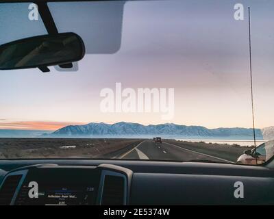 Der Innenraum eines Autos, das auf einer Landstraße gefahren wird Bei Sonnenuntergang Stockfoto