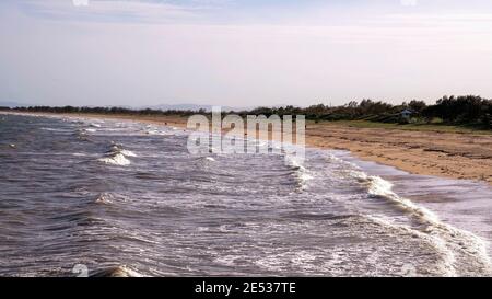 Wellen brechen an der Küste am beliebten Hafenstrand Stockfoto