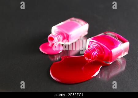 Beauty Hintergrund zwei Flaschen Nagellack-Flaschen rot oder burgunderrot pink Spill gegossen auf dem Tisch auf einem schwarzen Hintergrund mit einem Copyspace . Stockfoto