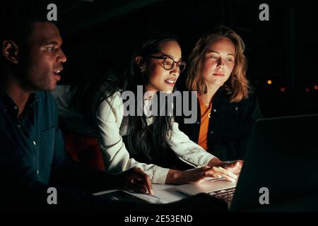 Multiethnische Gruppe von Geschäftsleuten, die spät mit einem Laptop arbeiten Nacht im Büro Stockfoto