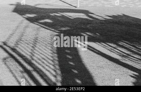 Schatten einer aufrechten Treppe und Geländer, auf das Gras eines Kinderspielplatzes geworfen. Stockfoto