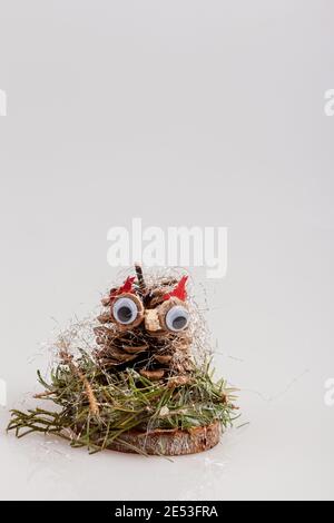 Kiefernkegel wie eine Eule auf einer Holzscheibe wie Eine Weihnachtsdekoration Stockfoto