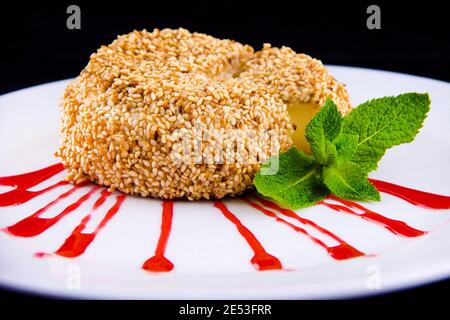 Frittierter Brie-Käse mit Sesam, garniert mit frischem Minzblatt und Preiselbeersauce. Stockfoto