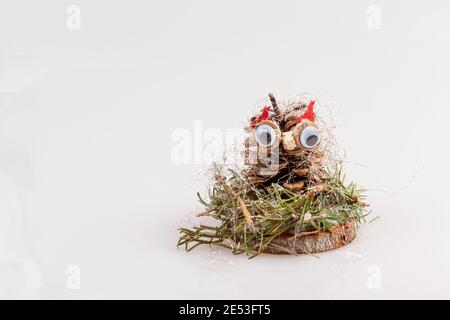 Kiefernkegel wie eine Eule auf einer Holzscheibe wie Eine Weihnachtsdekoration Stockfoto