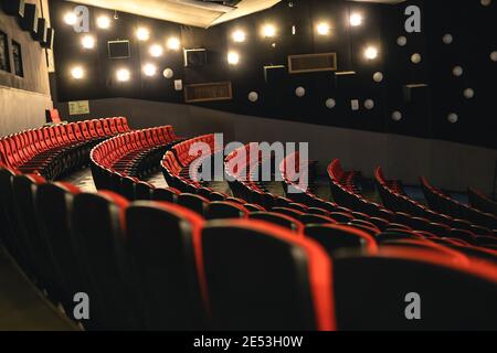 Kino-Interieur. Rote Sessel in einem großen leeren Kinosaal und eine spezielle Beleuchtung an den Wänden. Pandemie und Krise in der Industrie Stockfoto