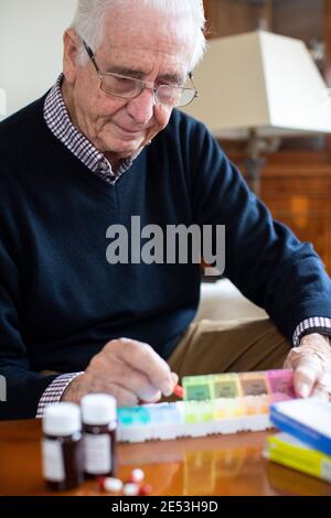 Älterer Mann Zu Hause, Der Medikamente In Den Tablettenspender Einführt Stockfoto