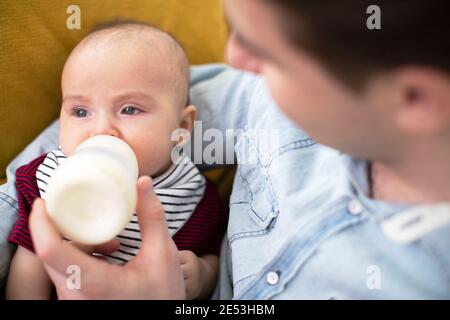 Nahaufnahme der liebevollen Fütterung baby Sohn mit Flasche zu Hause Stockfoto