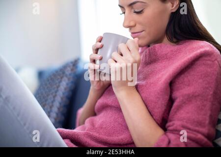 Junge Frau Entspannt Auf Sofa Zu Hause Mit Heißem Getränk Stockfoto