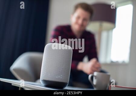 Der Mensch in der Lounge zu Hause Fragen Digital Assistant Frage Stockfoto