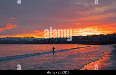 Portobello, Edinburgh, Schottland, Großbritannien. Januar 2021. Feuriger Sonnenaufgang für diesen Unterwasser-Kameramann und Filmmacher Mike Guest, am Ufer des Firth of Forth, mit den Hügeln von East Lothian im Hintergrund, die noch immer in einem kühlen Grad Celsius am Schnee festhalten. Stockfoto