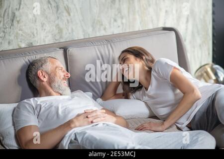 Fröhlicher Mann und Frau im Schlafanzug auf dem Bett Stockfoto