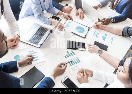 Dokumente, Gadgets und Hände von Personen auf dem Desktop, Draufsicht. Ein Team junger Geschäftsleute, die in einem Büro zusammenarbeiten und miteinander kommunizieren Stockfoto