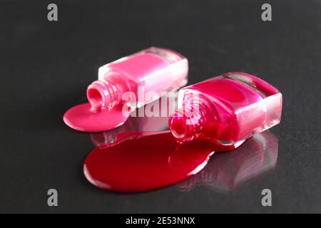 Beauty Hintergrund zwei Flaschen Nagellack-Flaschen rot oder burgunderrot pink Spill gegossen auf dem Tisch auf einem schwarzen Hintergrund mit einem Copyspace . Stockfoto