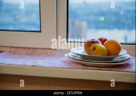 Äpfel auf einem Teller auf der Fensterbank. Selektiver Fokus mit geringer Schärfentiefe. Stockfoto