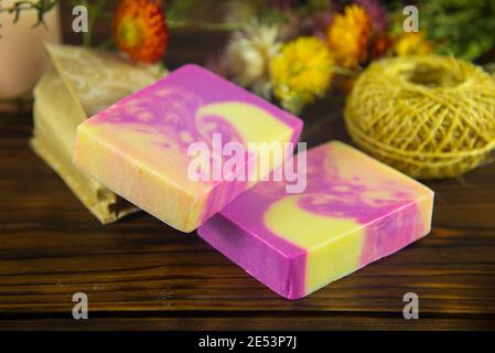 Natürliche handgemachte Hautpflege. Handgemachte Naturseife, Kerzen und Blumen auf der dunklen Holzplatte. Stockfoto