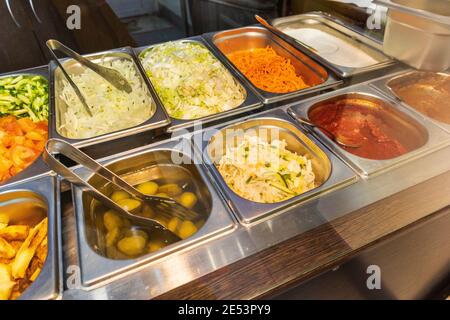 Theke in der Essenskantine Karotte Gurke Tomate Kartoffel Jalapeno Saucen Stockfoto