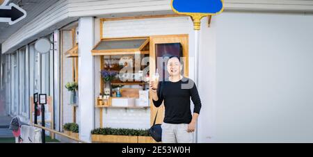 Asian Mann im schwarzen T-Shirt hält die Bubble Ball Ice Milk Tea vor dem Shop auf dem Outdoor-Straße Fußweg. Stockfoto