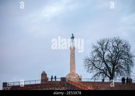 BELGRAD, SERBIEN - 12. DEZEMBER 2020: Touristen, die an einem sonnigen Nachmittag vor der Victor-Statue auf der Festung Kalemegdan stehen. Befindet sich in Kalemeg Stockfoto