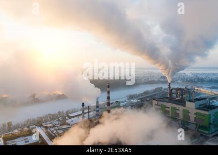 Rauch aus Fabrikschornsteinen auf dem Hintergrund des Sonnenaufgangs. Stockfoto