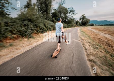 Der Mann reitet auf einem Longboard die Straße hinunter Stockfoto