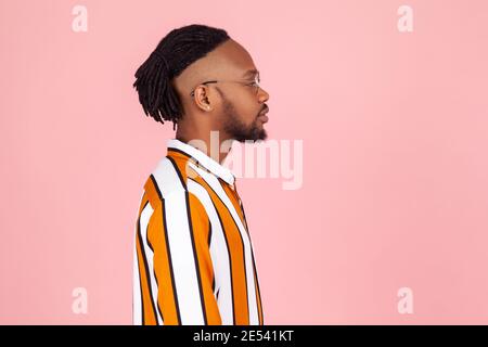 Profilportrait stilvoller afro-amerikanischer Mann mit Dreadlocks und Ohrpiercing im gestreiften Hemd ernsthaft nach vorne schauen, Zukunft planen. Studio im Innenbereich Stockfoto