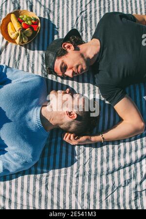 Zarte Gay paar Blick auf einander liegen auf Striped Tischdecke Picknick mit Obstkorb Stockfoto