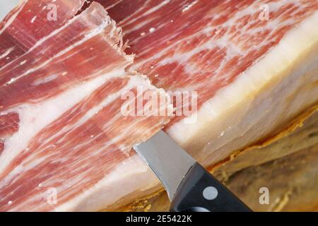 Schnitt von iberischem Schinken mit Eichelfütterung auf Metall- und Holzschinkenhalter, typisch spanische Feinschmeckerkost Stockfoto