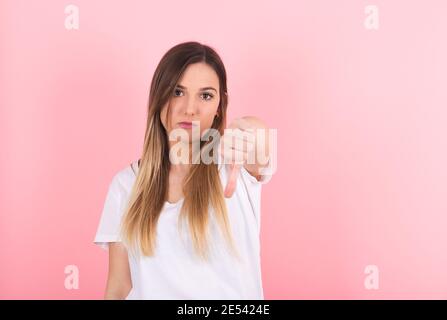 Junge Frau zeigt ihren Daumen nach unten. Geste der Missbilligung Stockfoto