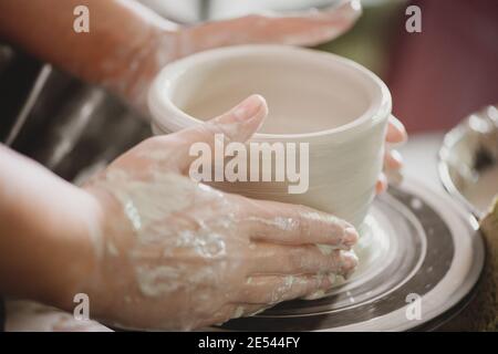 Nahaufnahme der Töpferhand, die ein irdntes Glas auf dem Kreis schafft. Stockfoto