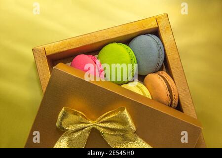 Verschiedene Farben und Geschmack Makronen in einer Goldbox auf Ein goldener Hintergrund Stockfoto