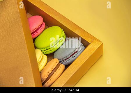 Verschiedene Farben und Geschmack Makronen in einer Goldbox auf Ein goldener Hintergrund Stockfoto