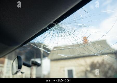Gebrochene Windschutzscheibe mit vielen Rissen und kleinen Glasstücken, beschädigtes Auto Stockfoto