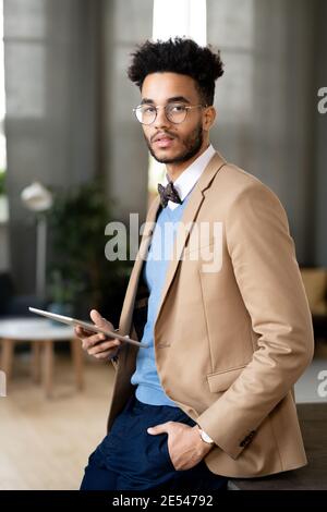 Porträt eines jungen Mannes in Mode Anzug Blick auf die Kamera Bei der Verwendung eines digitalen Tablets im Büro Stockfoto