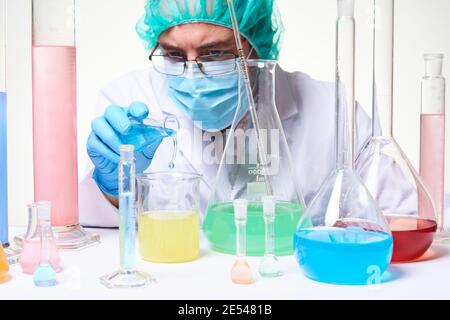 Laborwissenschaftler Techniker trägt Handschuhe, Gesichtsmaske und Laborkittel konzentriert während der Forschung und Durchführung von Experimenten im Labor Stockfoto