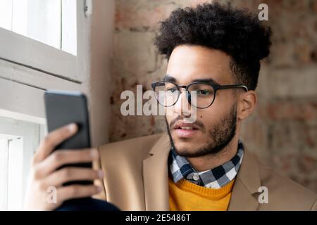 Junger Mann in Brillen halten Handy und lesen ein Nachricht Stockfoto