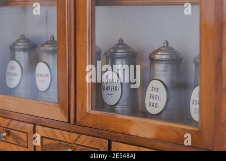 Regale mit Dosen in einer alten Apotheke. Schränke mit Glasregalen. Banken mit Medikamenten. Stockfoto