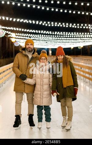 Porträt einer dreiköpfigen Familie, die beim Schlittschuhlaufen lächelt Auf der Eisbahn im Park Stockfoto