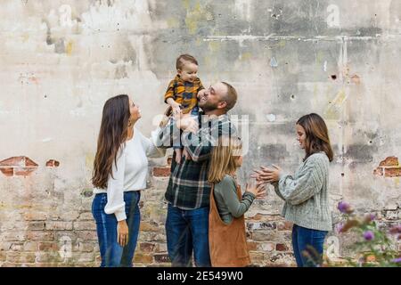 Eine fünfköpfige Familie mit zwei Mädchen und einem Baby Junge, der an einer urbane alte Ziegelmauer steht Stockfoto